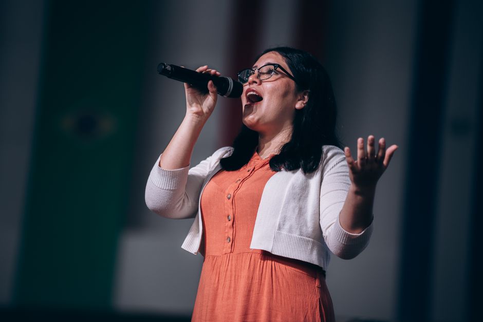Female singer performing passionately on stage with microphone in hand.